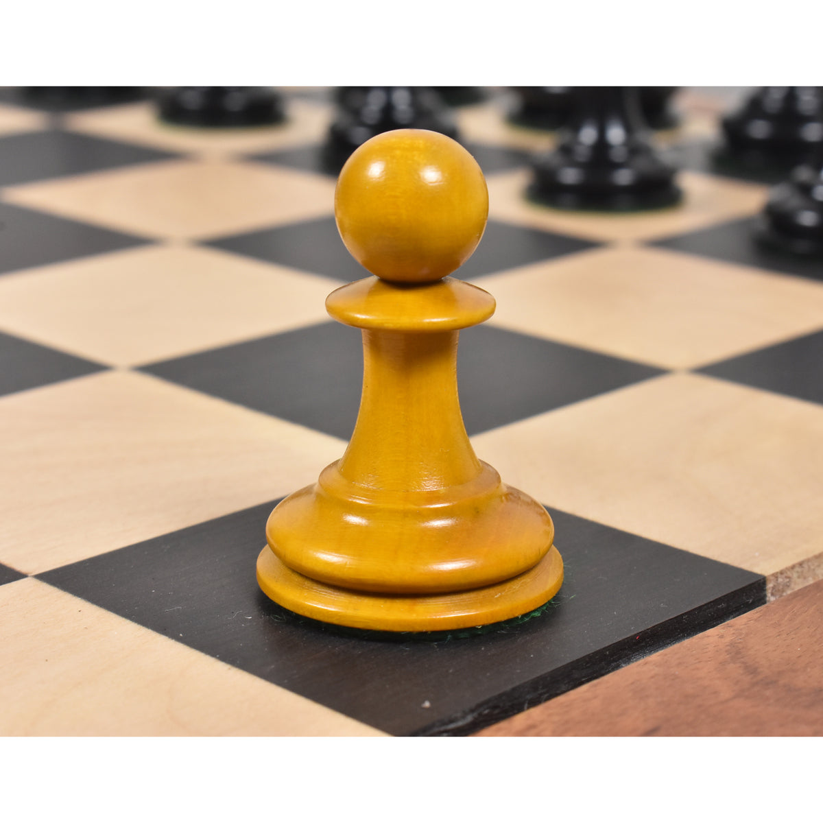 Antiqued boxwood Harrwitz Staunton pawn resting on a wooden chess board.