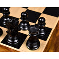 Detailed top view of an ebony wood knight, rook, and pawns on a glossy luxury wooden chessboard.