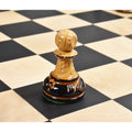 Macro shot of a Dubrovnik pawn chess piece in natural boxwood with a burnt ebonized base on a wooden chessboard.