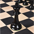 Triple weighted black ebony king piece showcasing fine craftsmanship on a wooden chessboard.