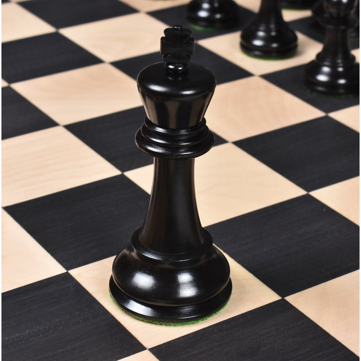 Triple weighted black ebony king piece showcasing fine craftsmanship on a wooden chessboard.