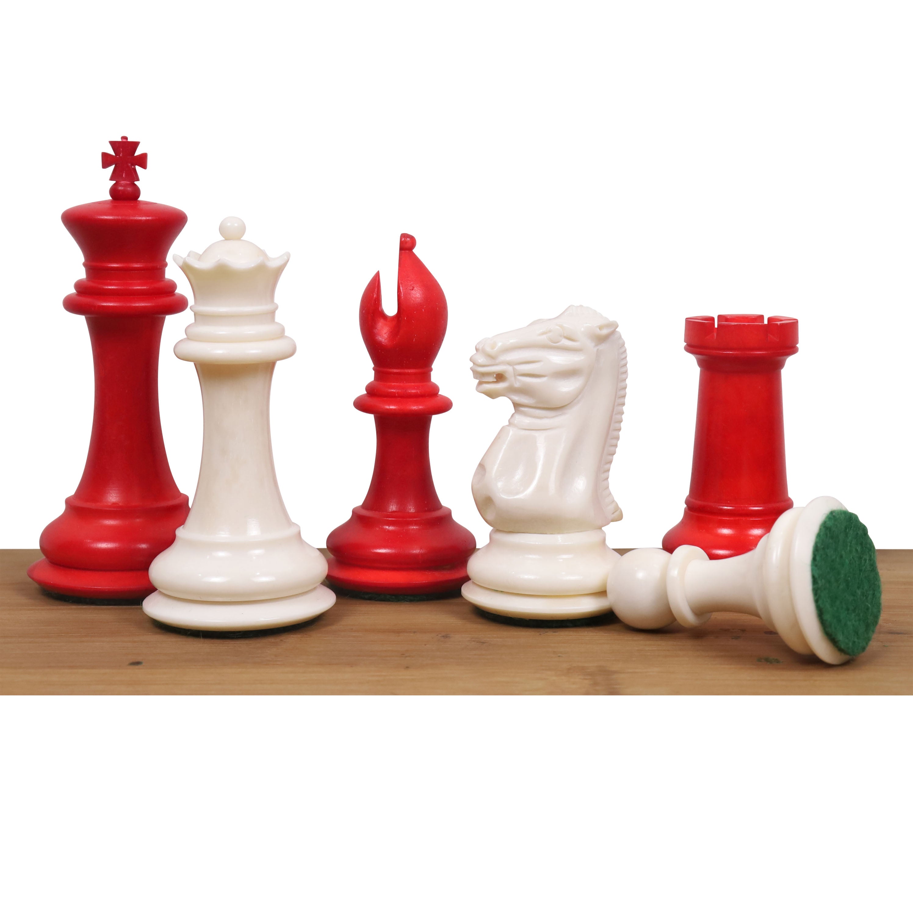 Crimson and white 1849 Jacques Cook camel bone chess pieces arranged on a wooden surface.