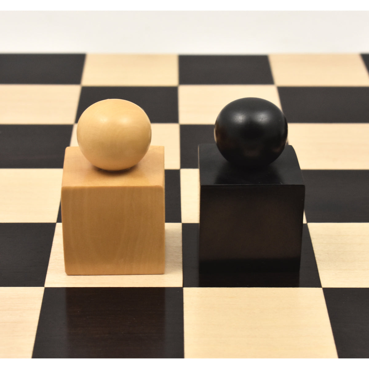Minimalist Bauhaus style ebonised boxwood king and queen pieces on a black and white chess board.