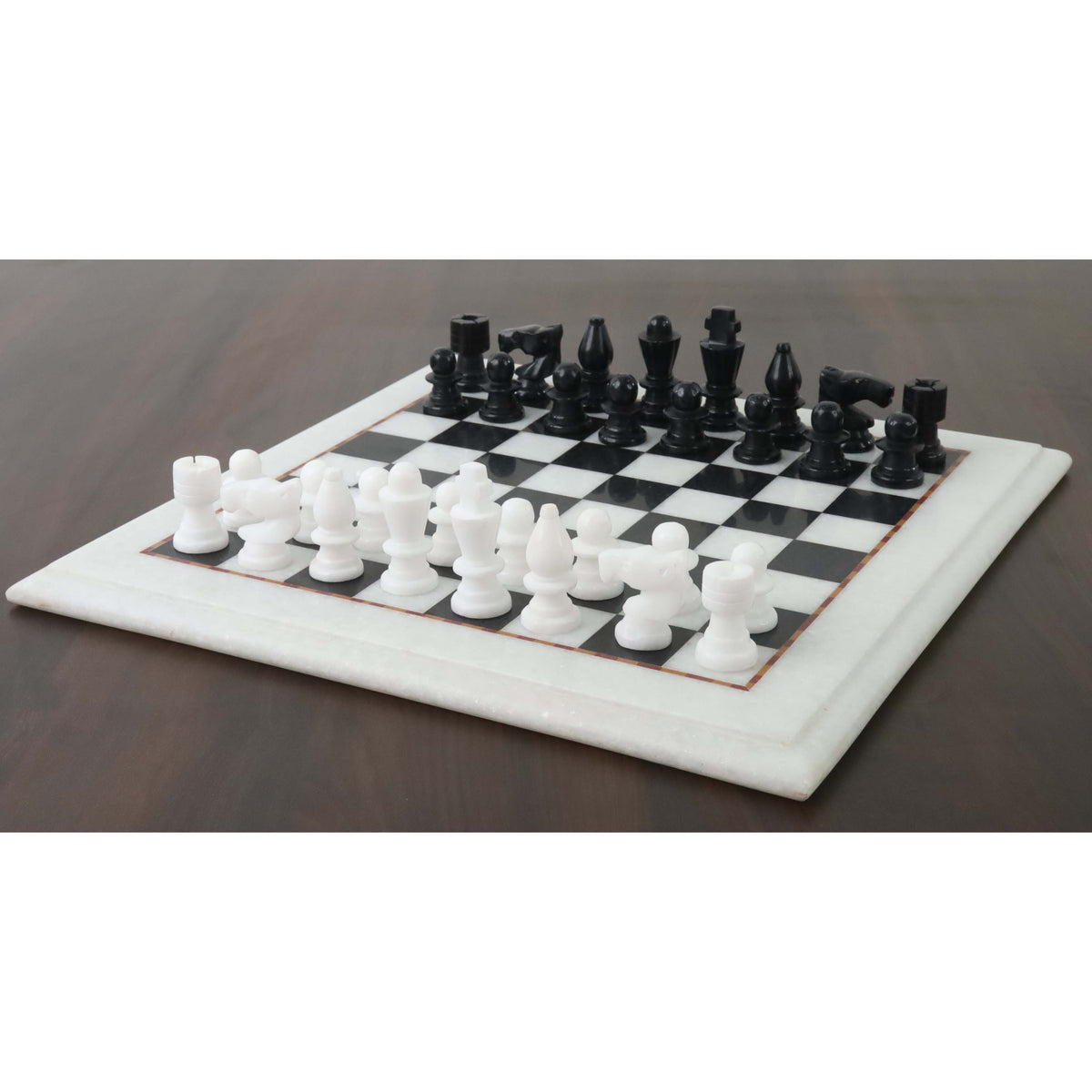 Handcarved 12-inch marble chess set arranged on a dark wooden surface.
