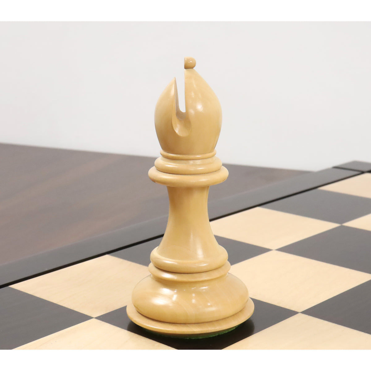 Single boxwood bishop piece from the mammoth luxury Staunton chess set standing on an ebony square.