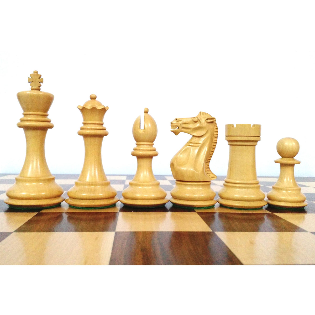 White Staunton chess pieces lined up on a wooden chessboard.