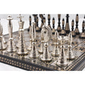Intricately crafted silver and black brass Warli chess pieces on a luxury board.