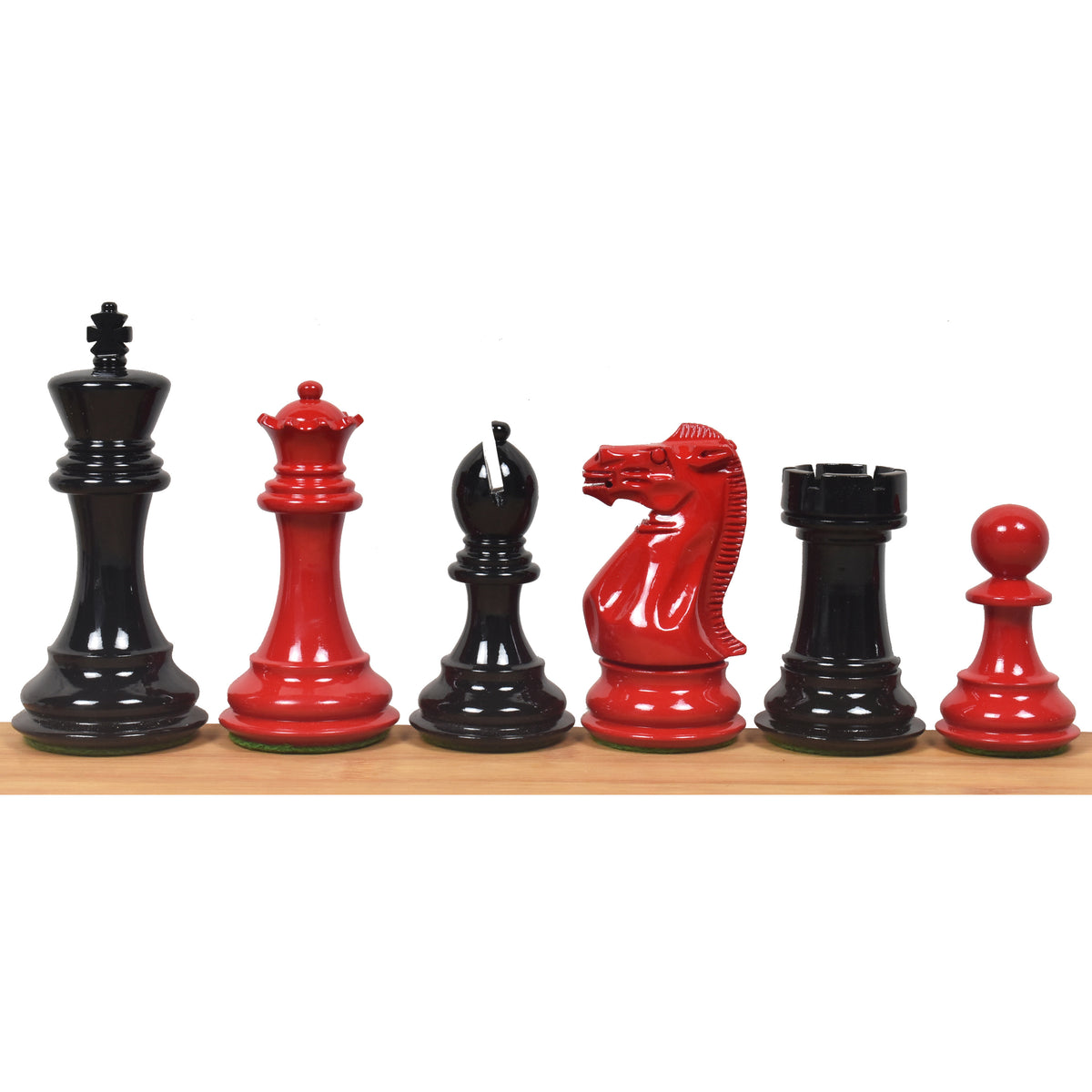 Red and black Staunton chess pieces lined up on a wooden surface.