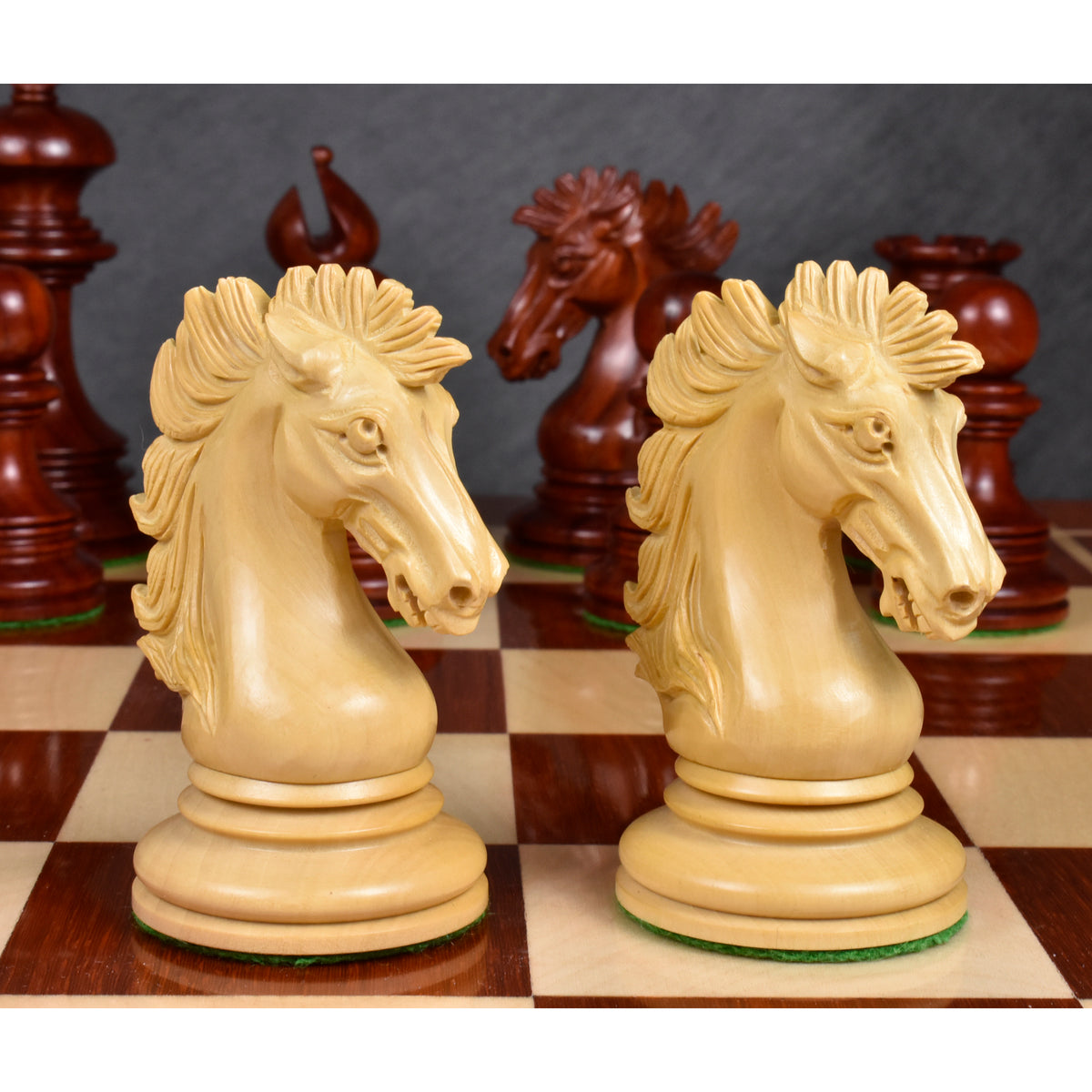 Two meticulously detailed natural boxwood knights from the Alexandria Staunton series on a chess board.