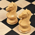 Pair of finely detailed boxwood Staunton knight chess pieces on a wooden chess board.