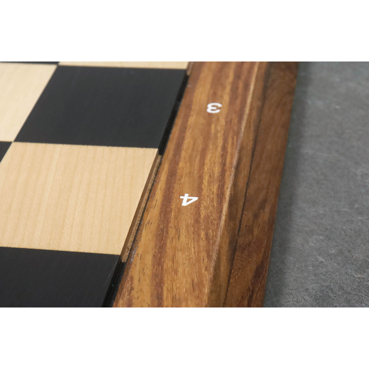 Detailed shot of the wooden border and engraved rank and file numbers on an Ebony and Maple professional chess board.
