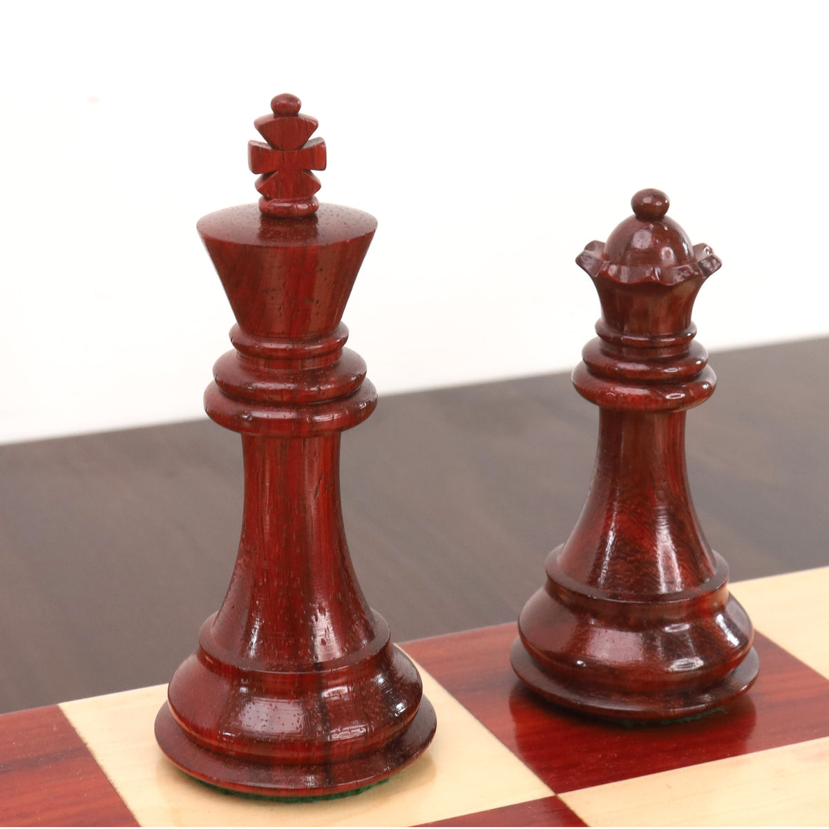 Premium 3.9 inch weighted bud rosewood king and queen pieces displaying rich grain textures on a chessboard.