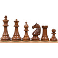 Dark golden rosewood French Grandmaster chess pieces displayed in a row on a wooden ledge.