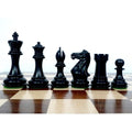 Ebonised wood Staunton chess pieces lined up on the board.