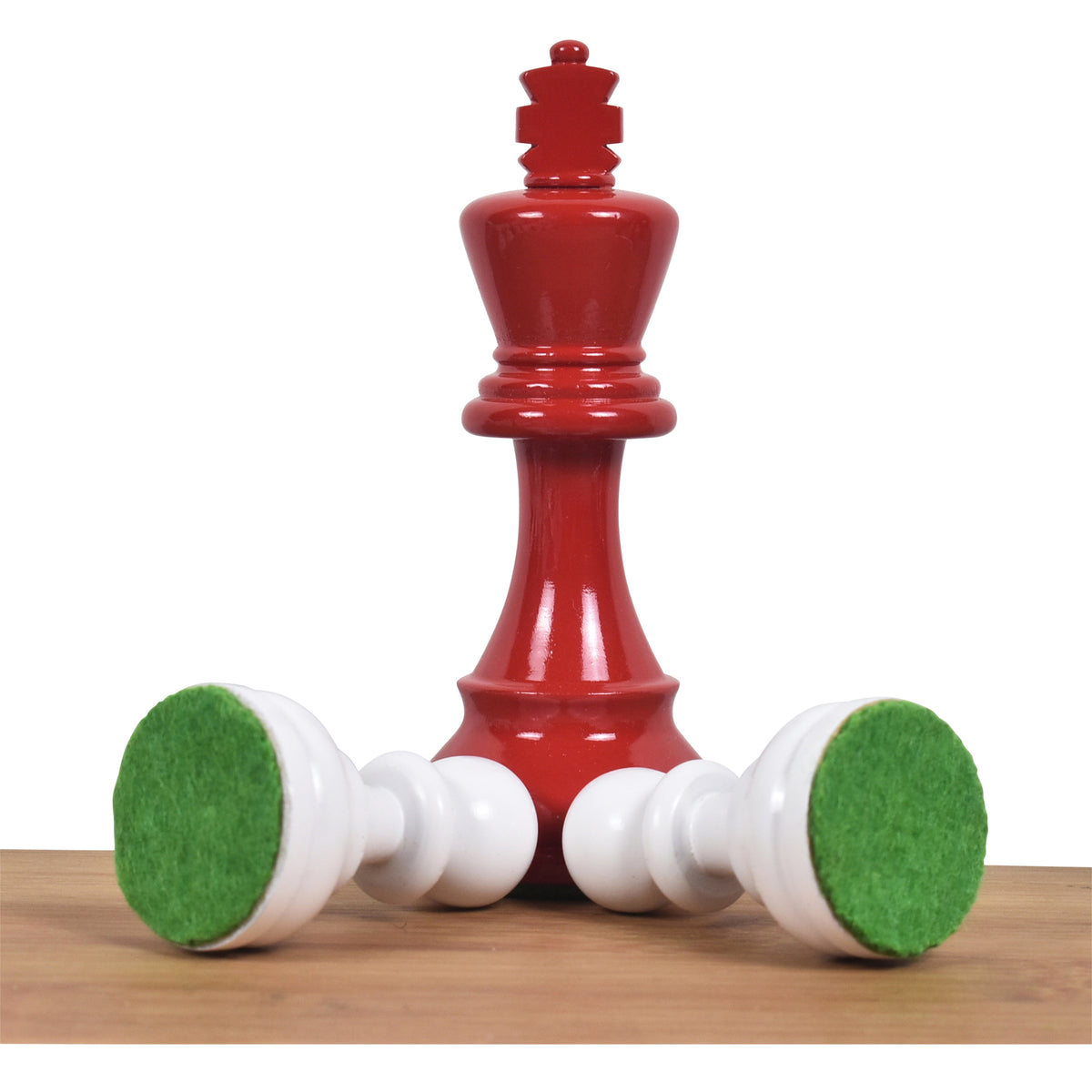 Standing red painted Staunton King behind two fallen ivory white pawns revealing green felt bases.