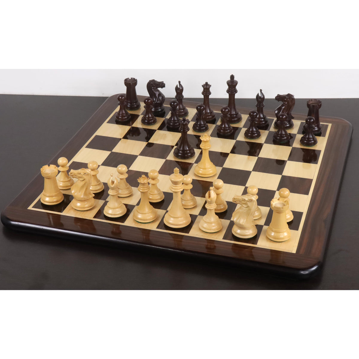 Complete 4-inch sleek Staunton luxury chess set in rosewood and boxwood set up in starting position on a wooden board.