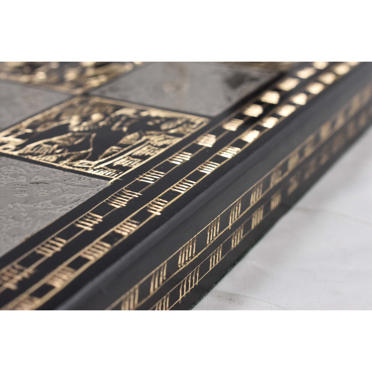 A macro view highlighting the detailed etched patterns and metallic texture along the side rail of the black and silver chess board.
