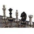 An angled view of the silver King, Queen, Bishop, Knight, and Rook lined up on the intricate silver and black chessboard.