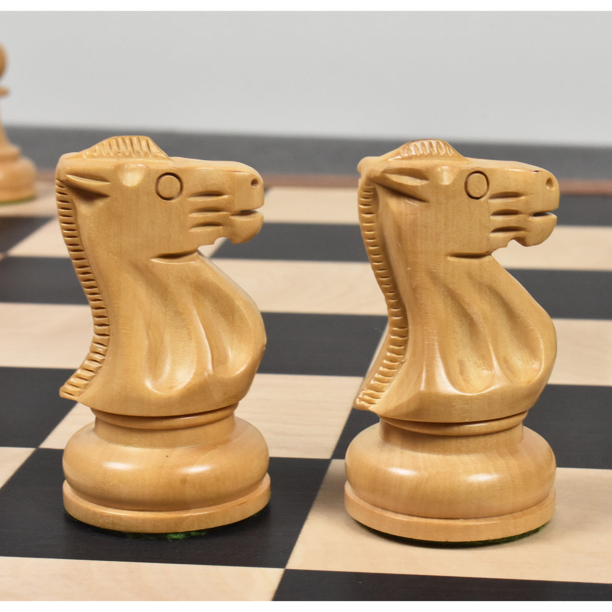Close-up profile of two carved natural boxwood knights from the Soviet Großmeister Supreme set on a wooden chessboard.