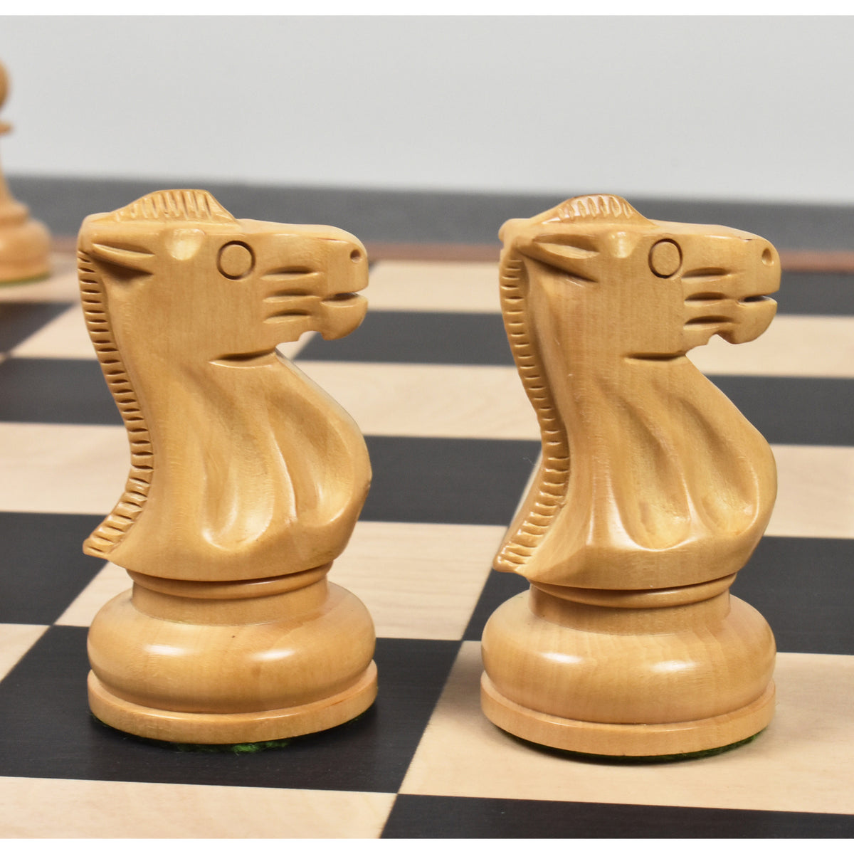 Two light boxwood knights of the Soviet Großmeister Supreme chess set facing each other on a chessboard.
