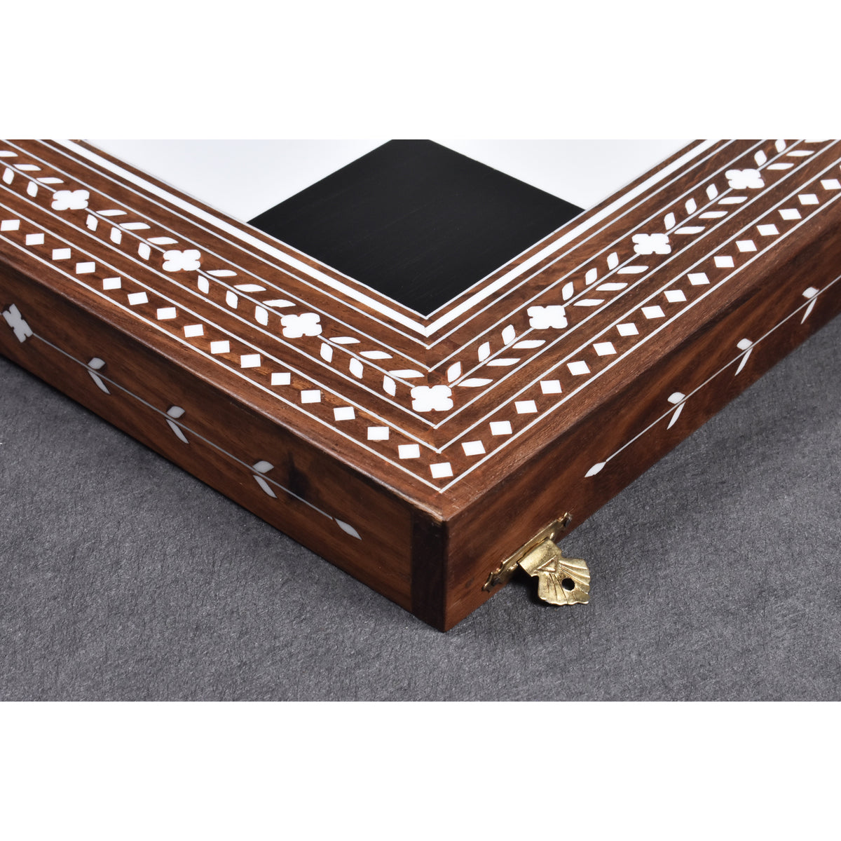 Detailed view of the corner construction and polished brass latches of a luxury 24-inch folding wooden chess board.