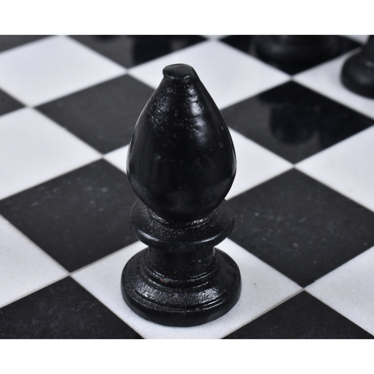 Macro shot of a single black marble chess bishop on the board.