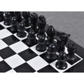 Close-up of black marble chess pieces arranged on a stone chessboard.