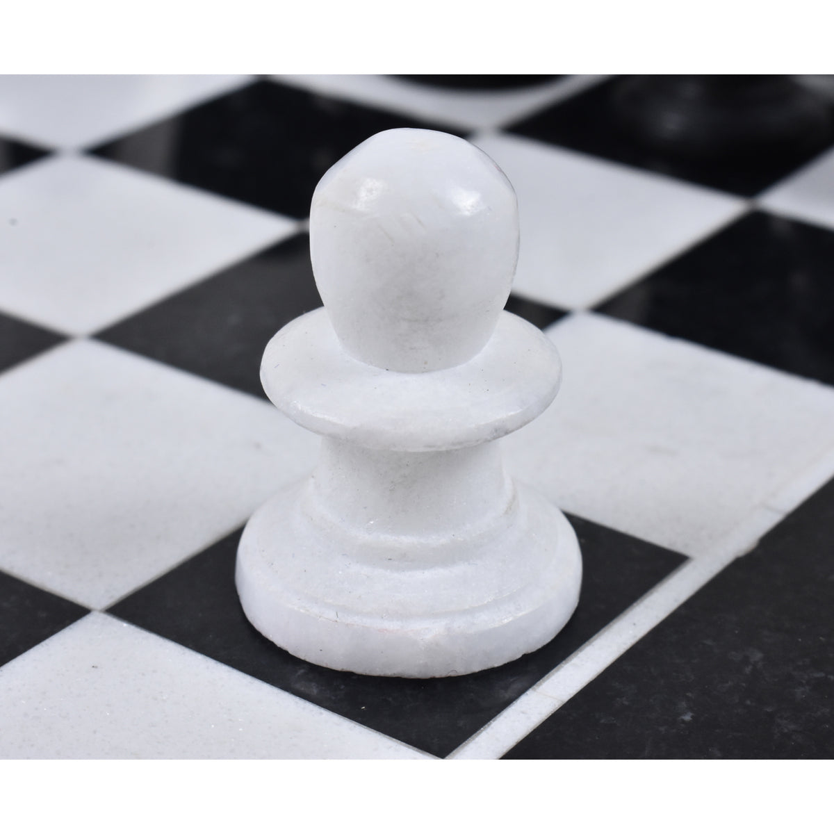 Macro shot of a single white marble pawn on the stone chessboard.