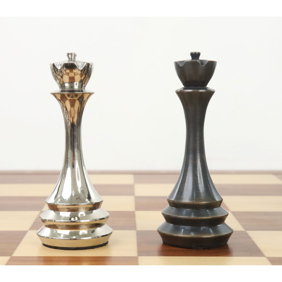 Side-by-side comparison of silver and antique finish brass metal luxury chess queens on a board.