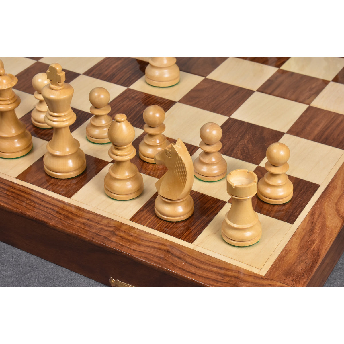 Close-up of polished boxwood chess pieces on a golden rosewood and maple inlaid board with a clear wood grain.