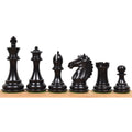 Dark ebony wood Alban Staunton chess pieces lined up from king to pawn on a wooden surface.