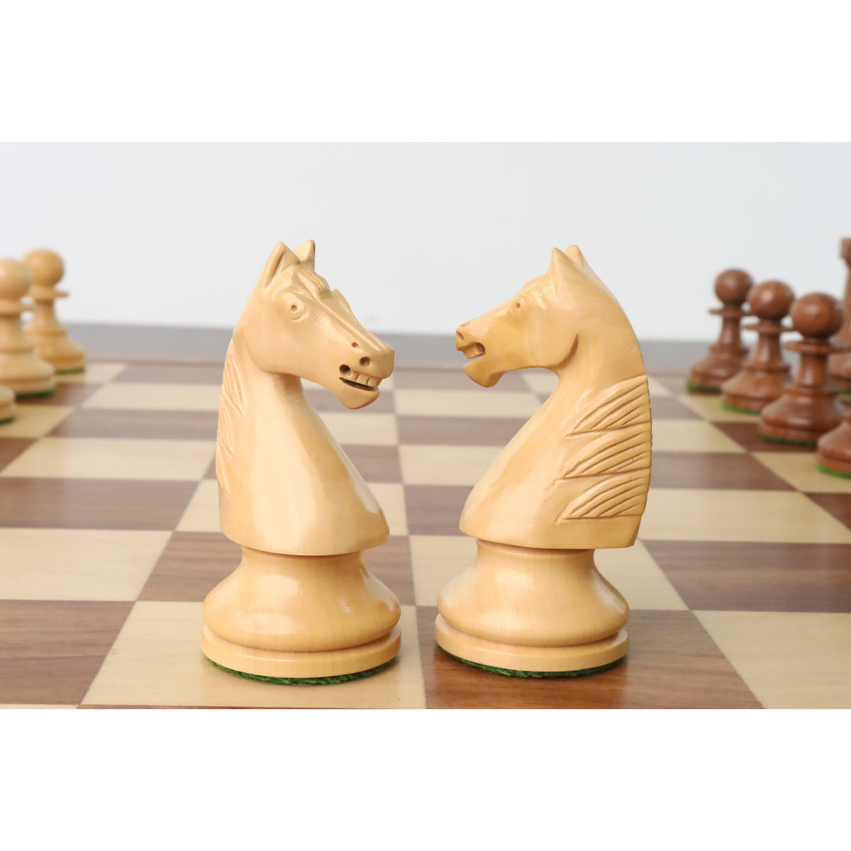 Boxwood French Grandmaster knight chess pieces facing each other on a wooden board.