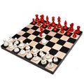 Red and ivory white painted Staunton chess pieces arranged in an active game position on a wood board.