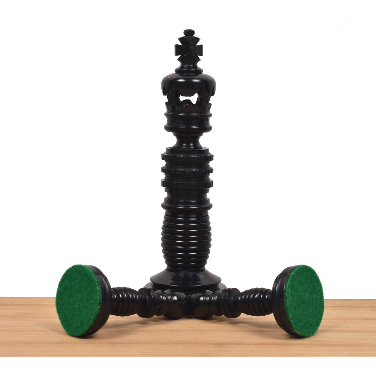 Black camel bone king piece standing upright next to toppled pieces showcasing green felt bases.
