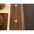 Close-up view of the clean rank and file letter engravings on the wooden border of the chess board.