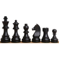 A row of dark ebonised boxwood tournament chess pieces showing detailed craftsmanship against white.