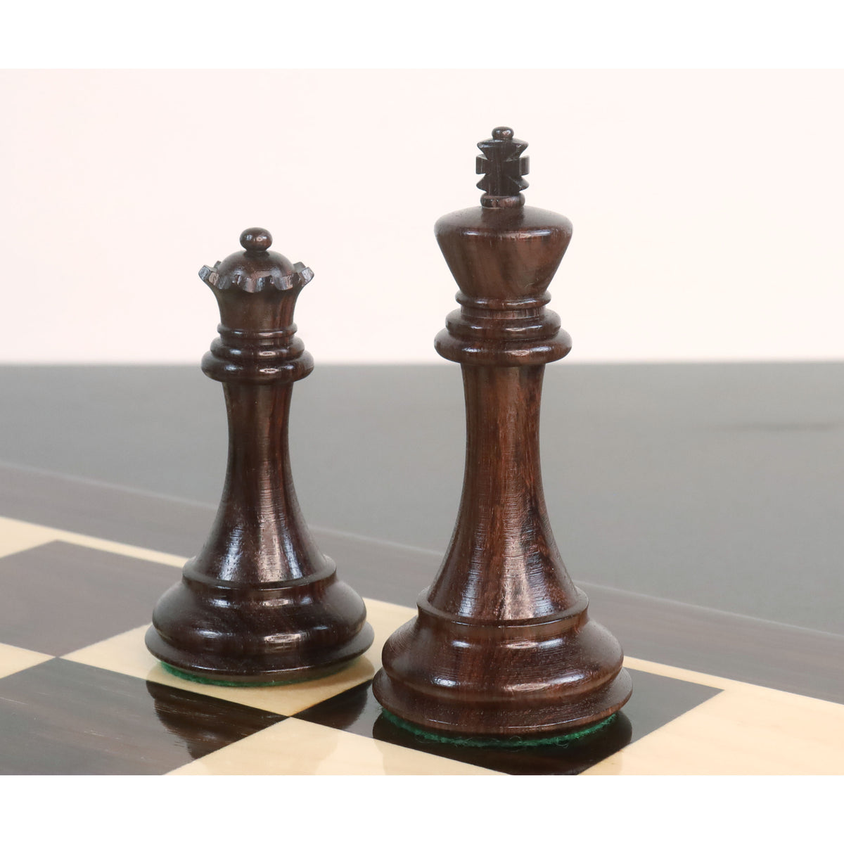 Dark rosewood king and queen from the 4-inch sleek Staunton luxury chess pieces, standing side-by-side on a glossy board.