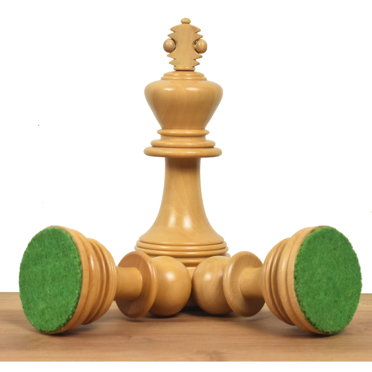 Upright boxwood king piece standing with two fallen pieces revealing green felted bases.