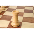 Boxwood French Grandmaster rook chess piece standing on a wooden chessboard.