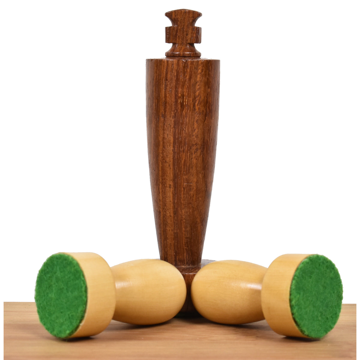 Golden rosewood king piece standing behind two overturned boxwood pawns with green felt bases.