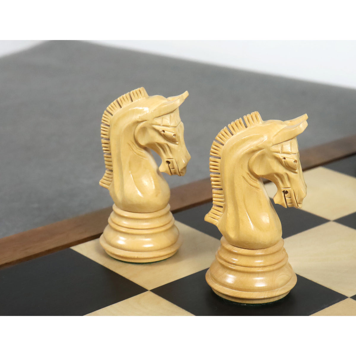 Close-up of two finely carved light knights from the 3.8" Imperial Staunton ebony chess pieces set on a board.