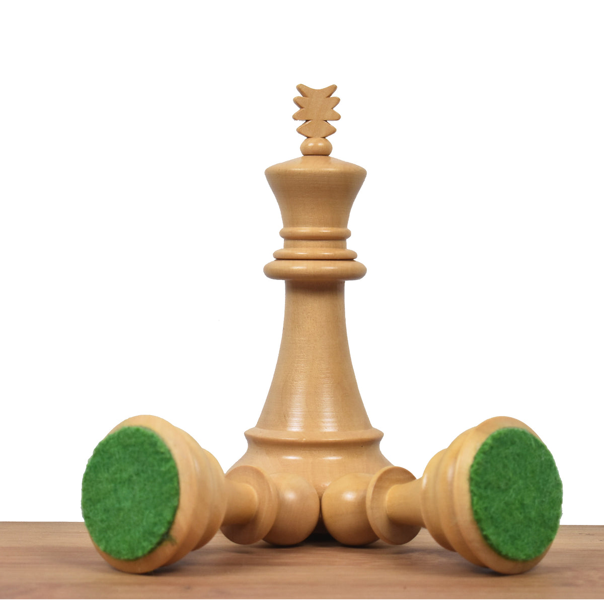 Boxwood king piece standing with two overturned pieces showing premium green felt bases.