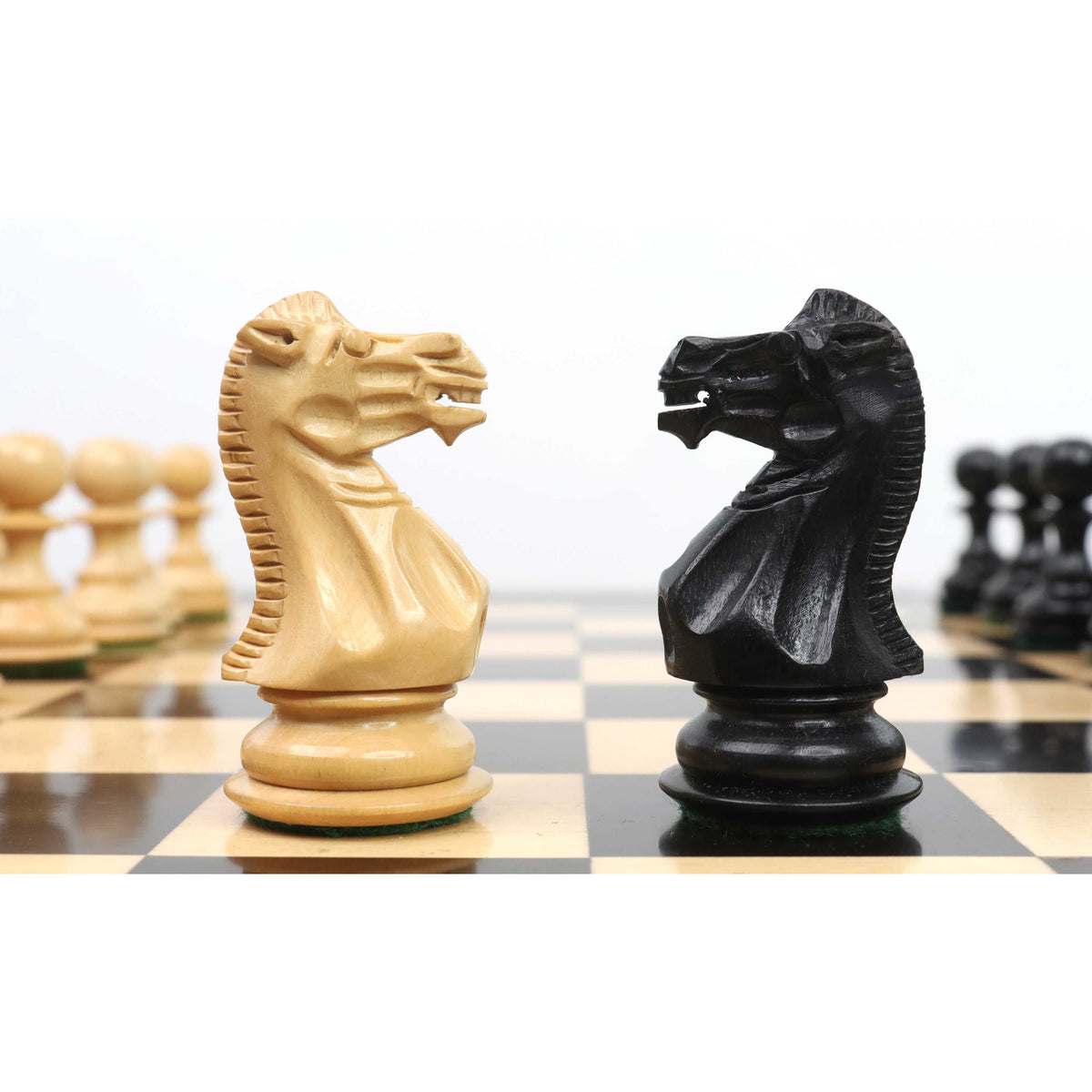 Intricately carved boxwood and ebony wood Knights facing each other on a checkered board.