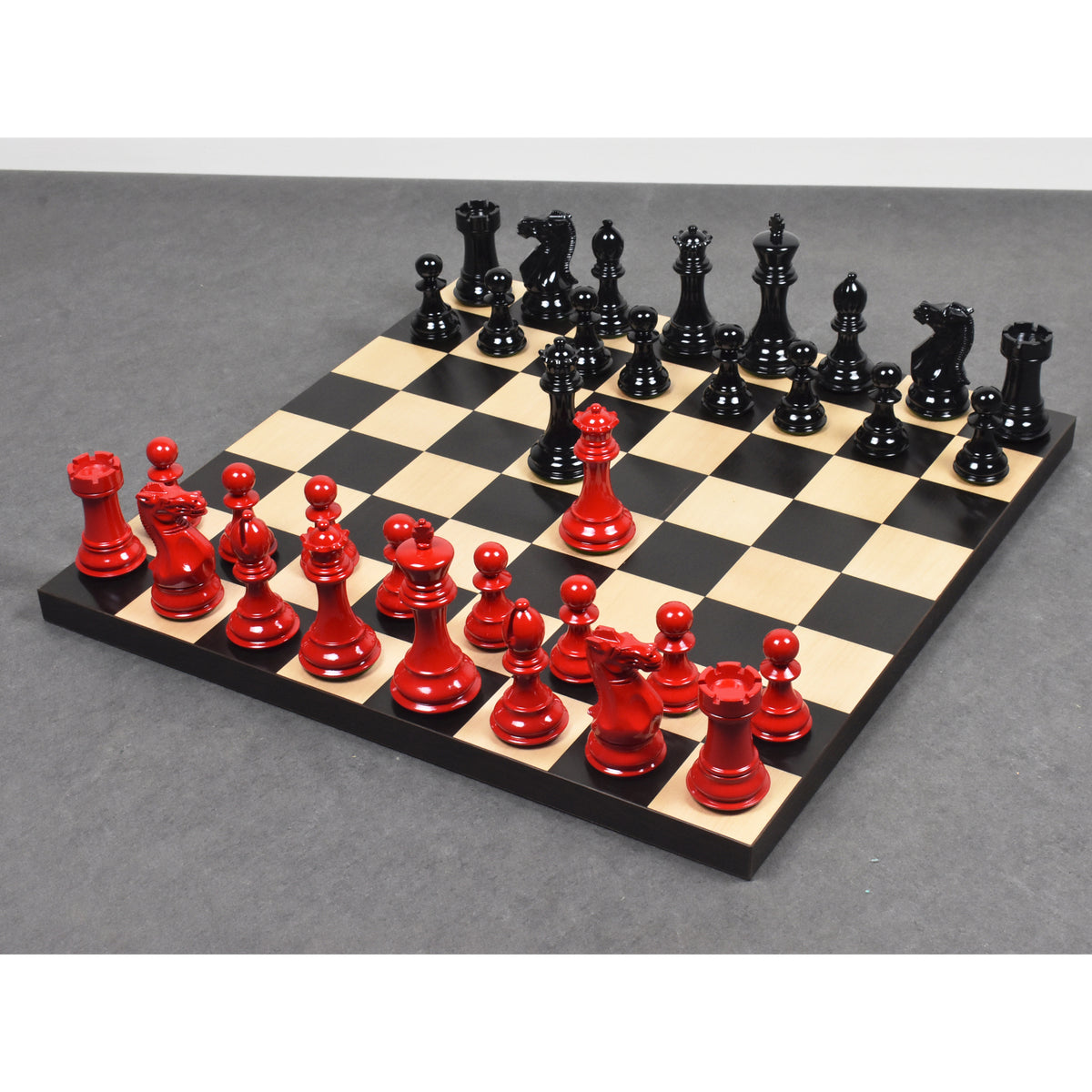 A high-angle view of a chess game in progress with red and white Pro Staunton pieces on an ebony and maple board.