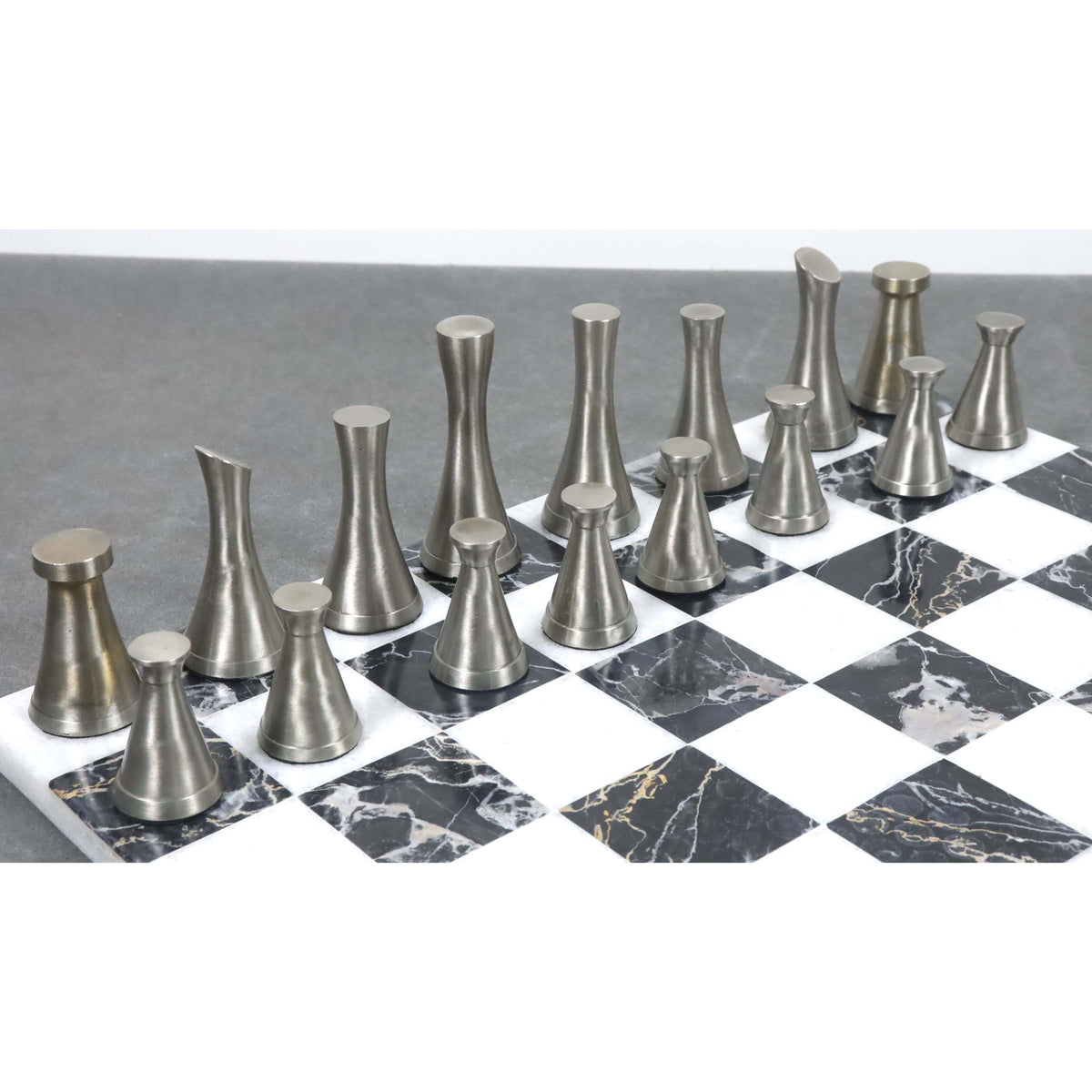 Side view of silver finished Tower Series metal chess pieces on a black and white marble board.
