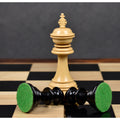 Boxwood king piece standing upright on a glossy board behind fallen ebony pieces revealing green felt bases.