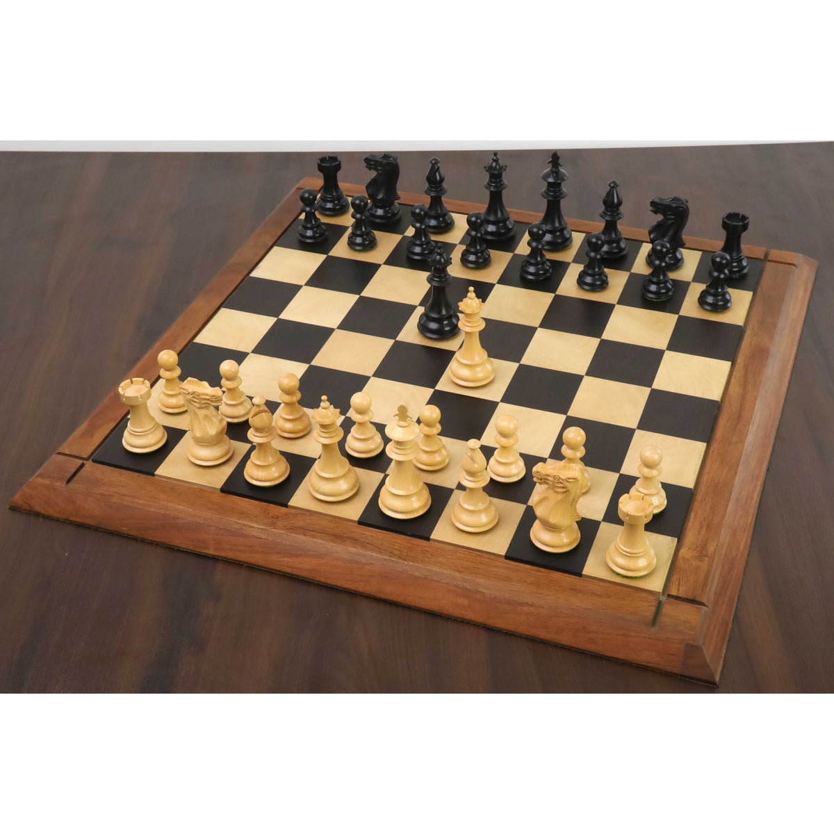 3.7" British Staunton ebonised boxwood chess pieces set up on a wooden board during a game.