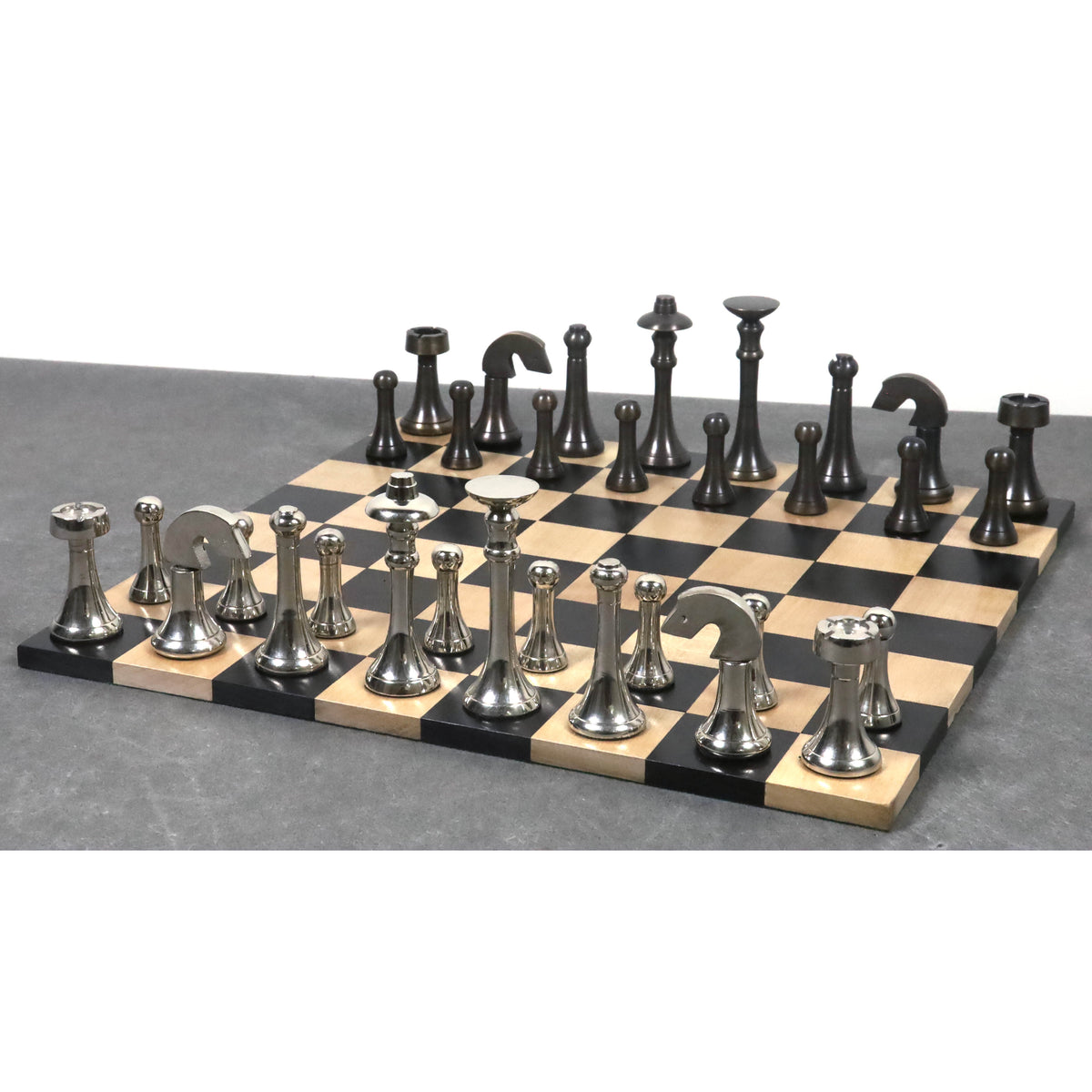 Full contemporary brass luxury chess set in silver and antique finishes on a chess board.