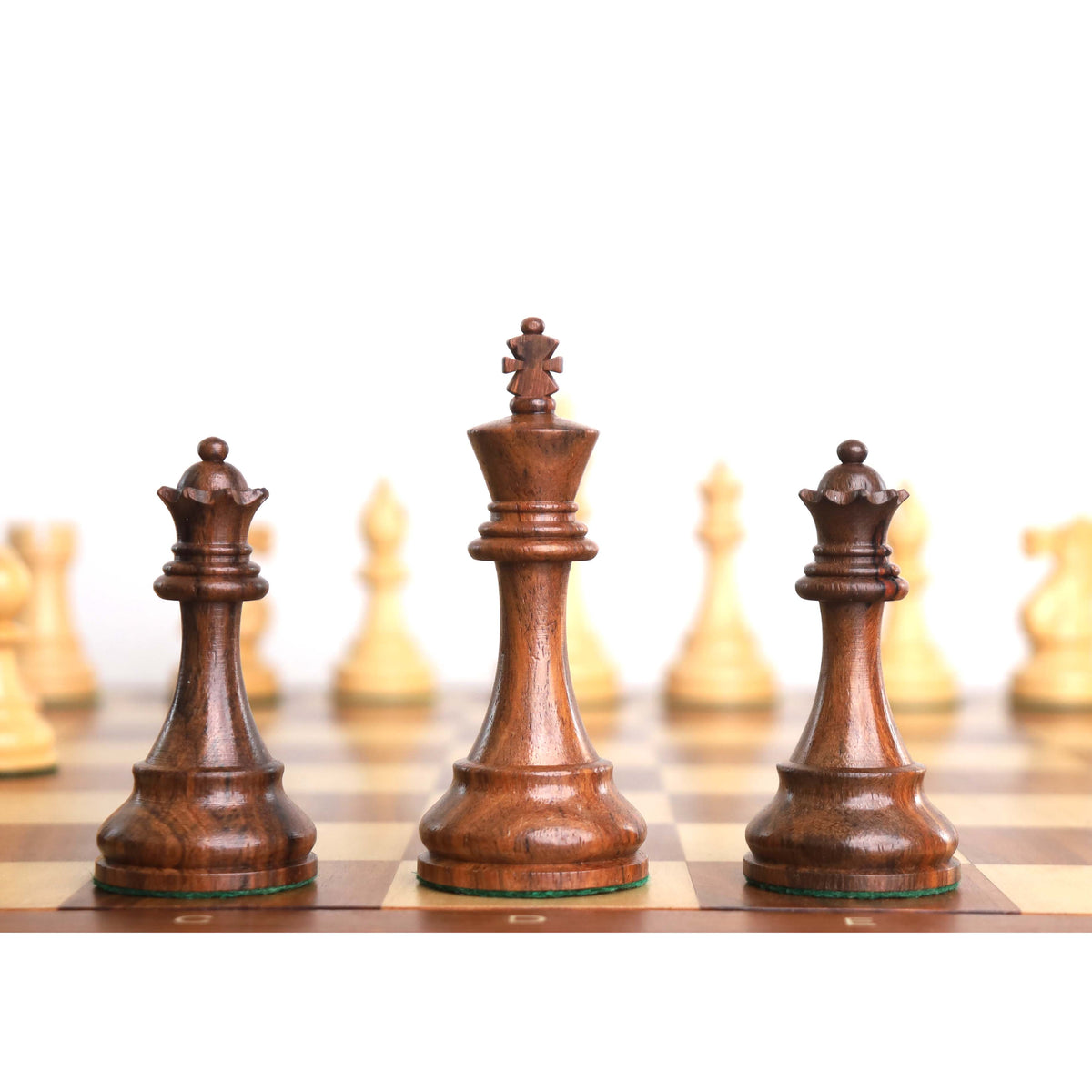 Weighted golden rosewood Staunton King positioned between two extra Queens on a chessboard.