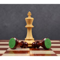 A standing Boxwood king towers over two fallen Bud Rosewood pawns from the 3.9" Craftsman Staunton chess set on a board.